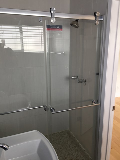 A glass shower stall with a white toilet in the corner.