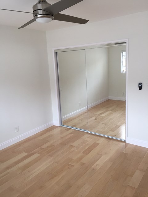 A room with a ceiling fan and a sliding glass door.
