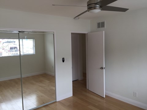 A room with a ceiling fan and a glass door leading to another room.