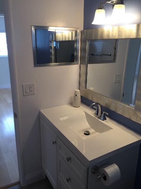 A bathroom with a sink, mirror, and light.