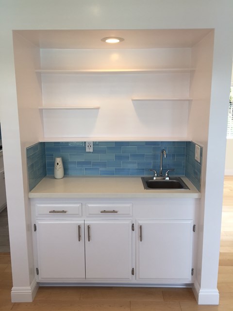 A kitchen with white cabinets and a blue tile backsplash.