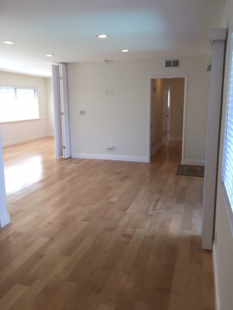 A room with wooden flooring and white walls.