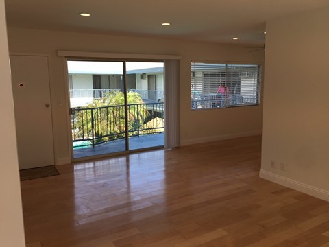 A room with wooden floors and a view of a balcony with a railing.