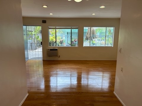 A room with wooden floors and a window overlooking a patio.