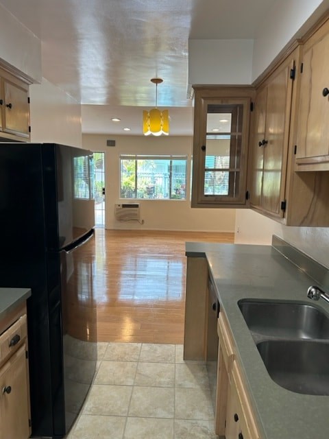 A kitchen with wooden cabinets and a black refrigerator.