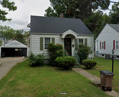 A small house with a grey roof and a white garage door.