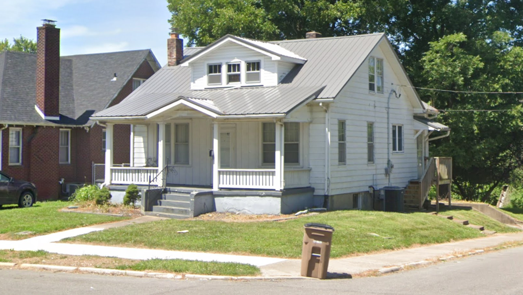 A white house with a grey roof and a chimney.