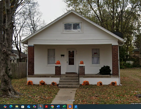 A small white house with a red brick chimney and a front porch.