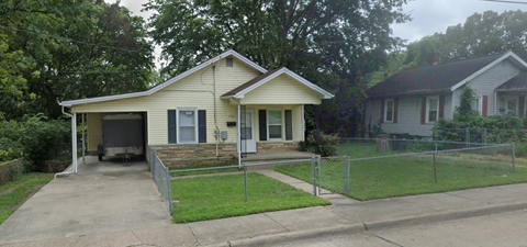 A house with a garage and a fence in front of it.