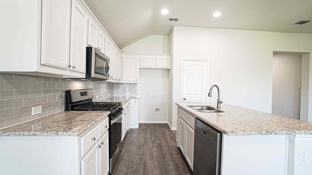 A kitchen with white cabinets and a granite countertop.