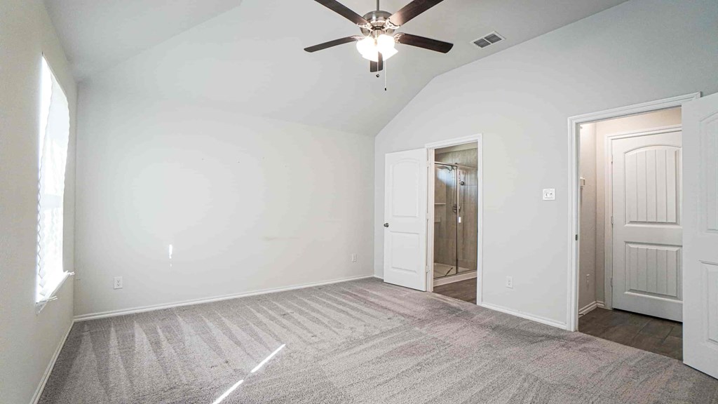 A room with a ceiling fan and carpeted floor.