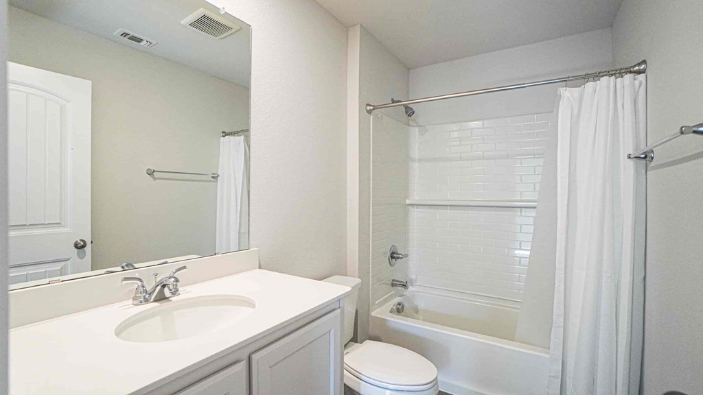 A white bathroom with a toilet, sink, and shower.