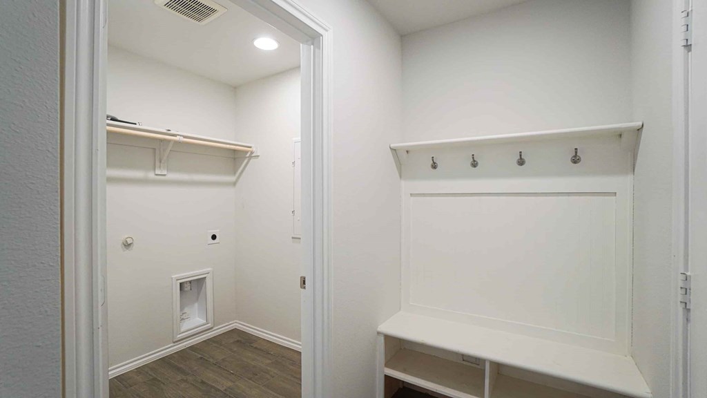 A white closet with a shelf and a bench.
