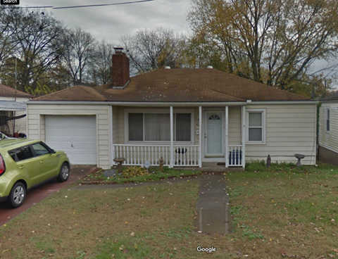 A green car is parked in front of a house.
