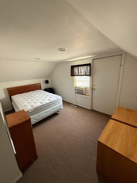 A bedroom with a bed, dresser, and window.