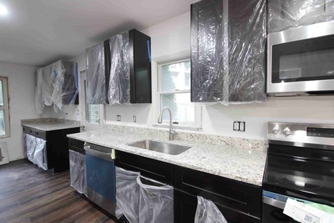 A kitchen with black cabinets and appliances is under construction.