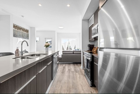 A modern kitchen with a stainless steel refrigerator and wooden flooring.