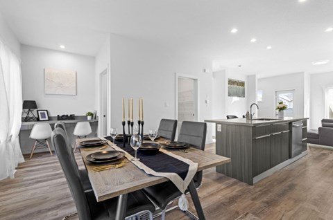 A modern dining room with a wooden table set for two.