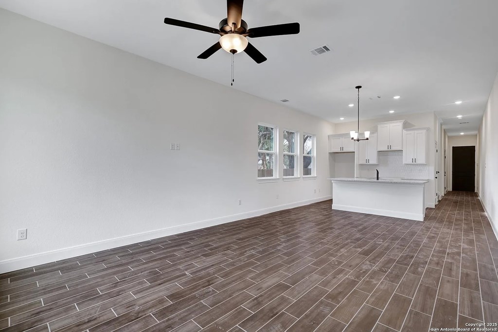 A room with a ceiling fan and wooden flooring.
