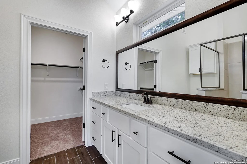 A bathroom with a marble countertop and white cabinets.