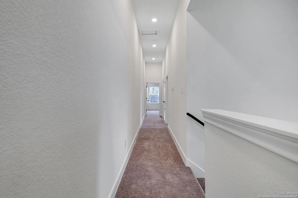 A long hallway with a carpeted floor and white walls.
