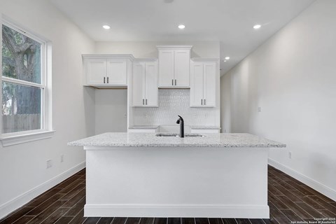 A kitchen with white cabinets and a marble countertop.