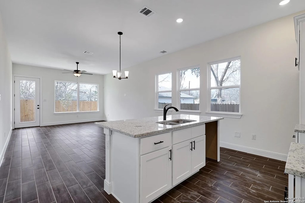 A kitchen with white cabinets and a marble countertop.