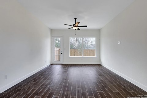 A room with a ceiling fan and wooden flooring.