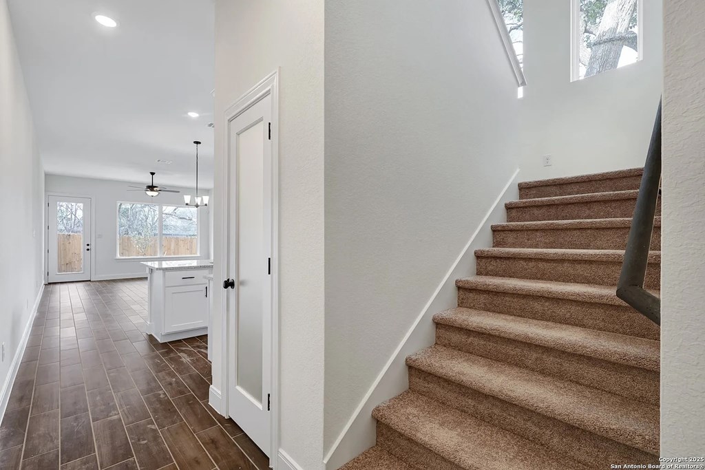 A staircase with a carpeted runner and a black handrail.