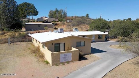 A building with a sign that reads "Clifton" is surrounded by a dirt road and vegetation.