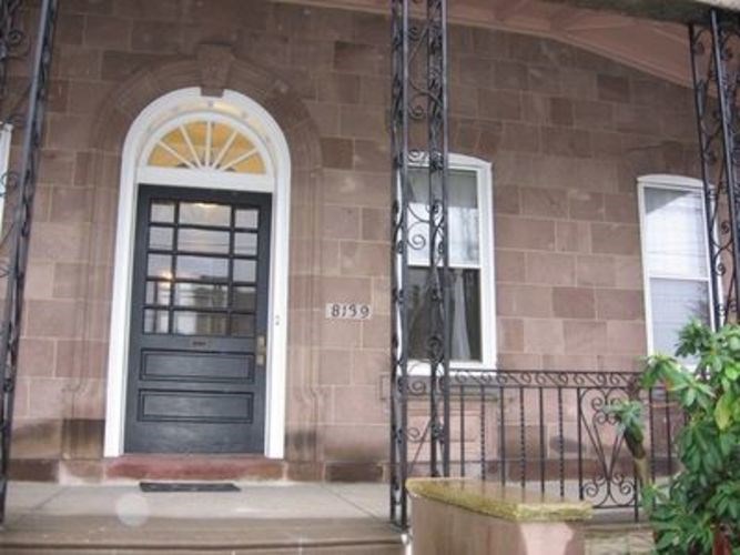 A house with a black door and a window with bars.
