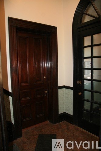 A dark wooden door with a glass panel and a black door frame.