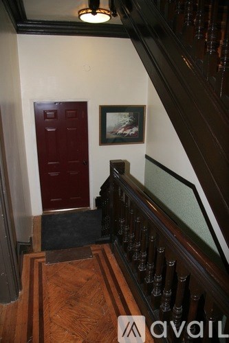 A wooden staircase with a red door and a framed picture on the wall.