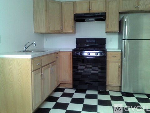 A kitchen with wooden cabinets and a black and white checkered floor.