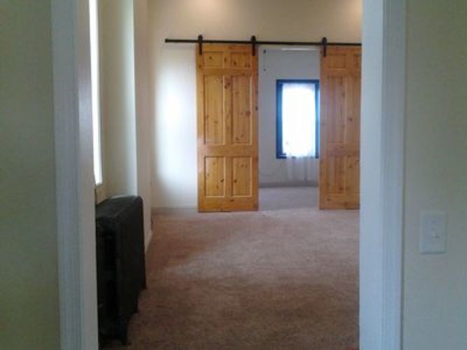 A room with a black couch and a pair of wooden doors.