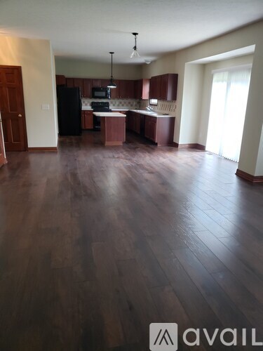 A spacious kitchen and living room with dark wood flooring.