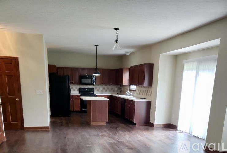 A kitchen with dark wood cabinets and a black refrigerator.
