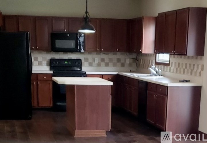 A kitchen with brown cabinets and a black refrigerator.