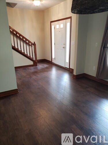 A hallway with wood floors and a staircase.