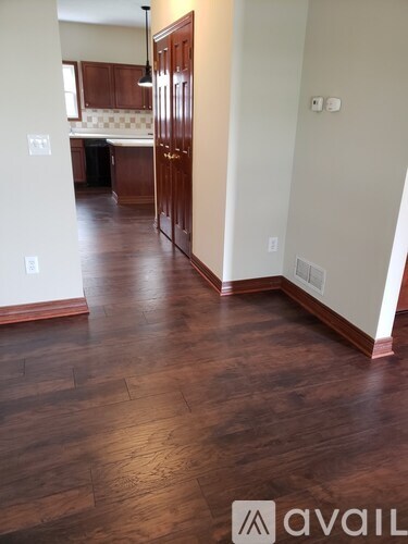 A hallway with wood floors and a white wall.