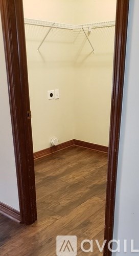 A hallway with a coat rack and wooden floors.
