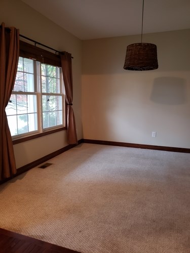 A room with a window and a hanging light fixture.