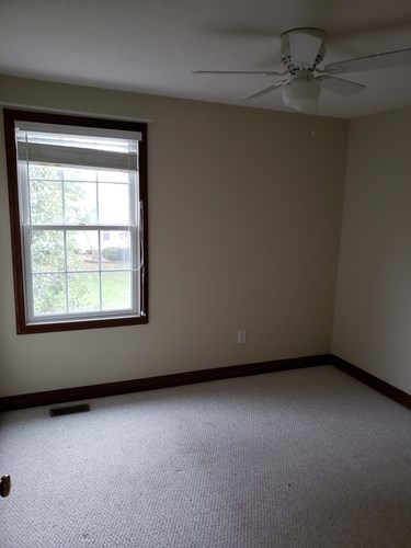 A room with a window and a ceiling fan.