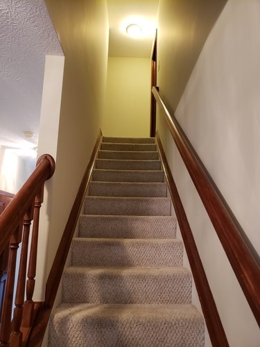 A staircase with a carpeted runner and wooden balusters.