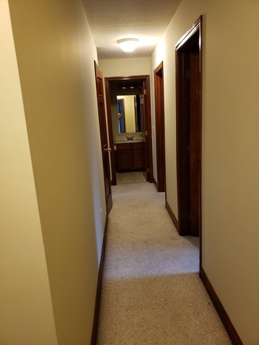 A hallway with a carpeted floor and white walls.