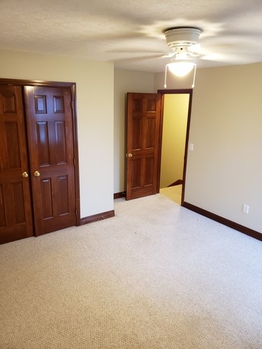 A room with a carpeted floor and two wooden doors.
