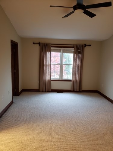 A room with a ceiling fan and a window with curtains.