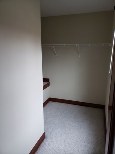 A small, empty room with a carpeted floor and a white wall.