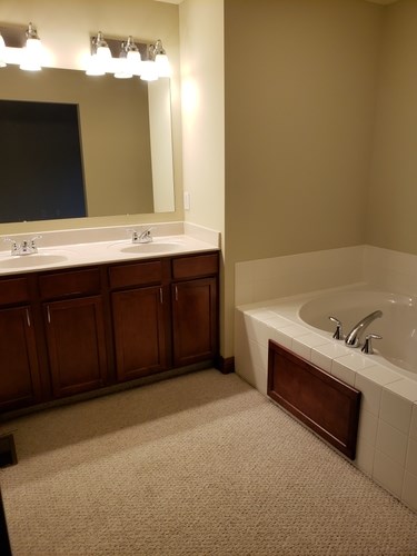 A bathroom with a white tub and a mirror above a sink.