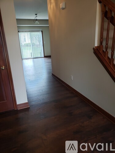 A hallway with wood floors and a staircase.